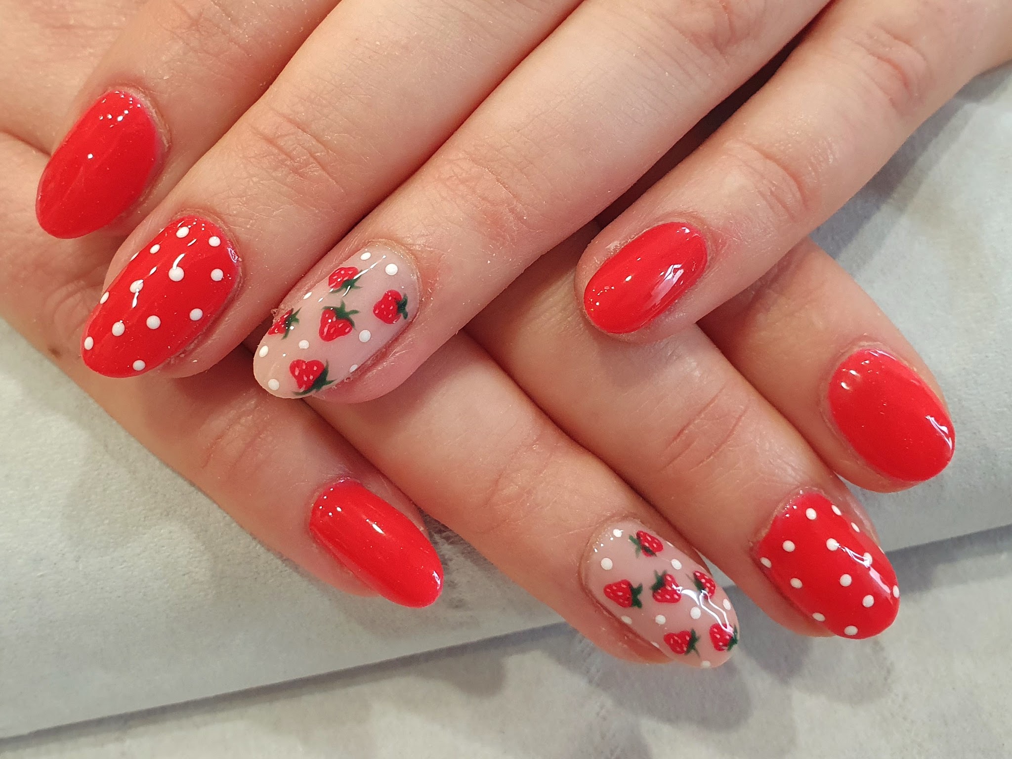 Red nails with white polka dots and hand-painted strawberries
